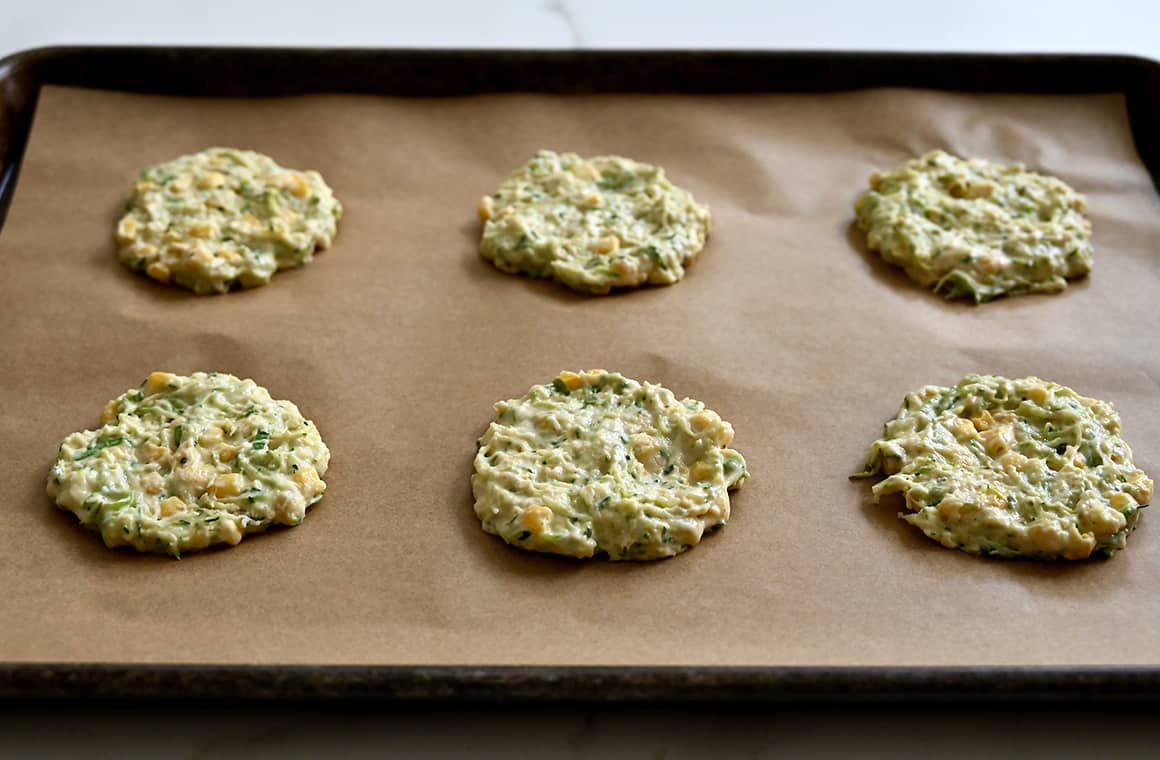 Unbaked fritters on a parchment paper-lined baking sheet