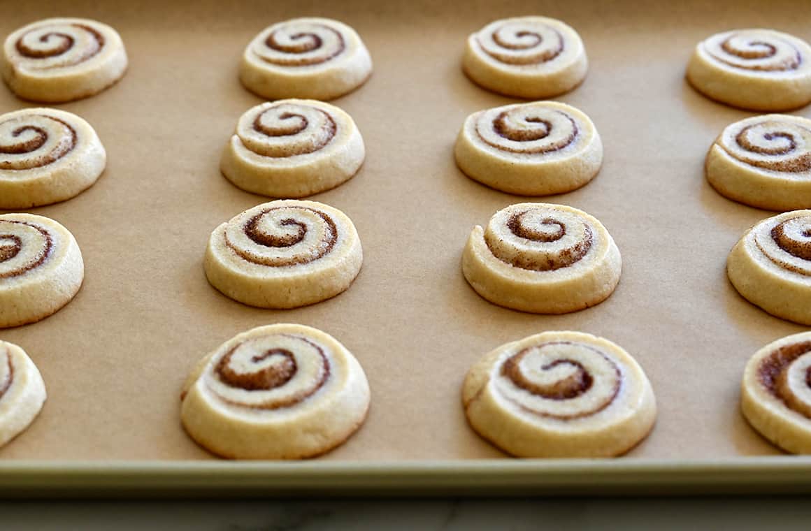 Baked cinnamon roll cookies on a parchment paper-lined baking sheet