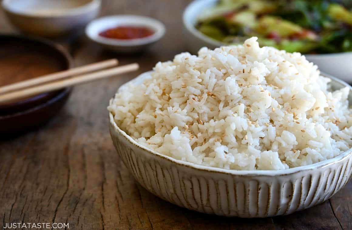 Creamy Coconut Rice piled high in a serving bowl next to chopsticks
