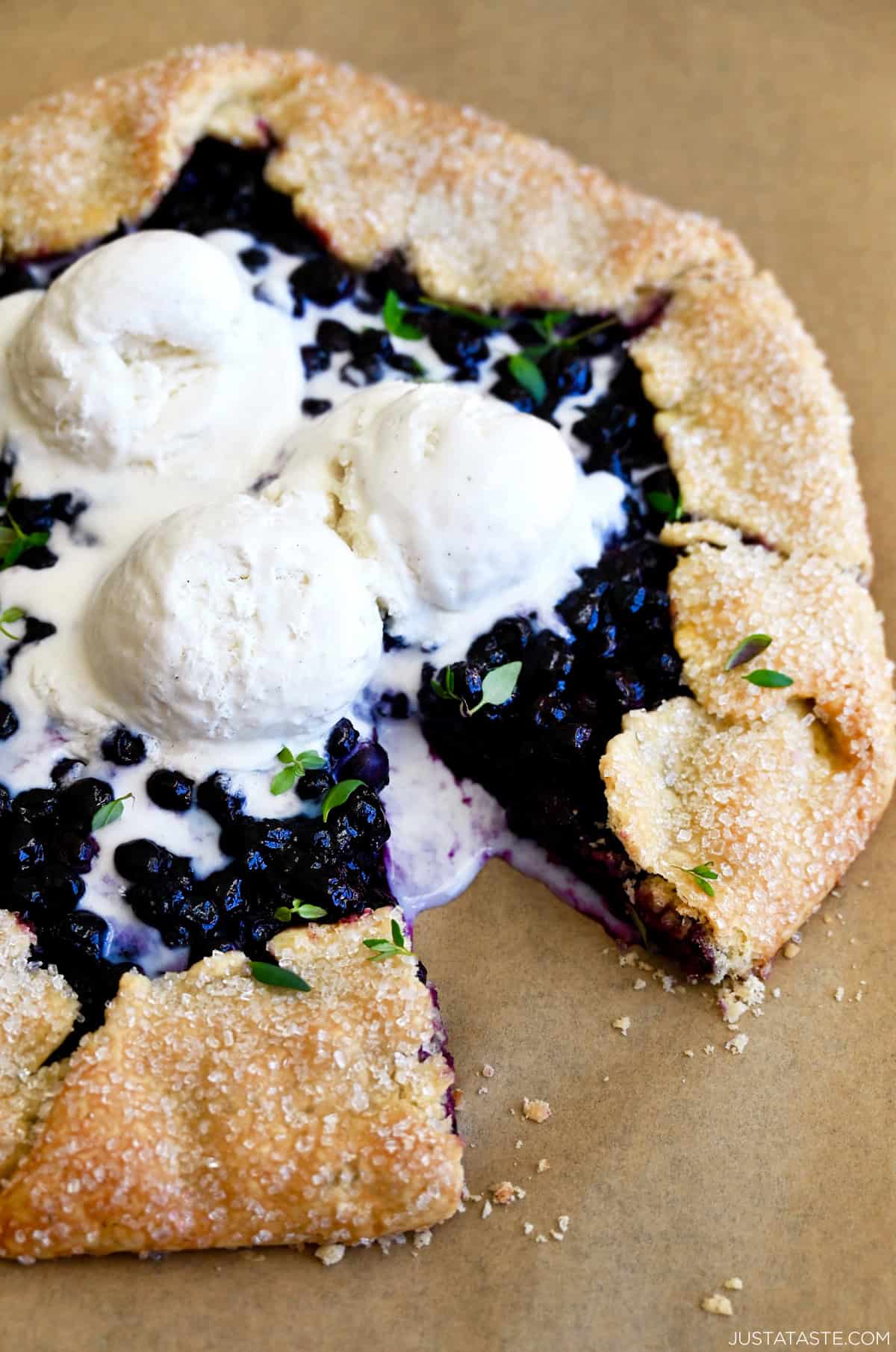 A homemade Blueberry Galette topped with three scoops of vanilla bean ice cream and fresh thyme.