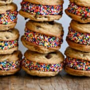 Three tall stacks of chocolate chip cookie ice cream sandwiches with rainbow sprinkles.