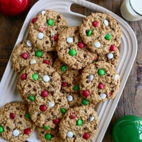 A top-down view of the best Christmas Monster Cookies studded with red, green and white M&Ms on a white serving platter