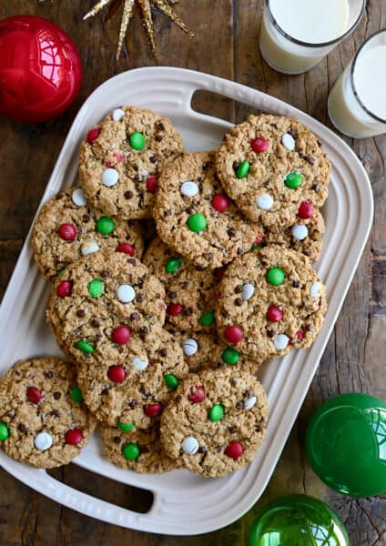 A top-down view of the best Christmas Monster Cookies studded with red, green and white M&Ms on a white serving platter