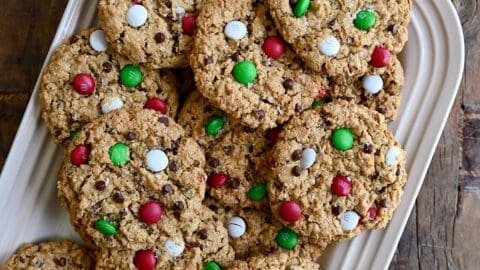 A top-down view of the best Christmas Monster Cookies studded with red, green and white M&Ms on a white serving platter