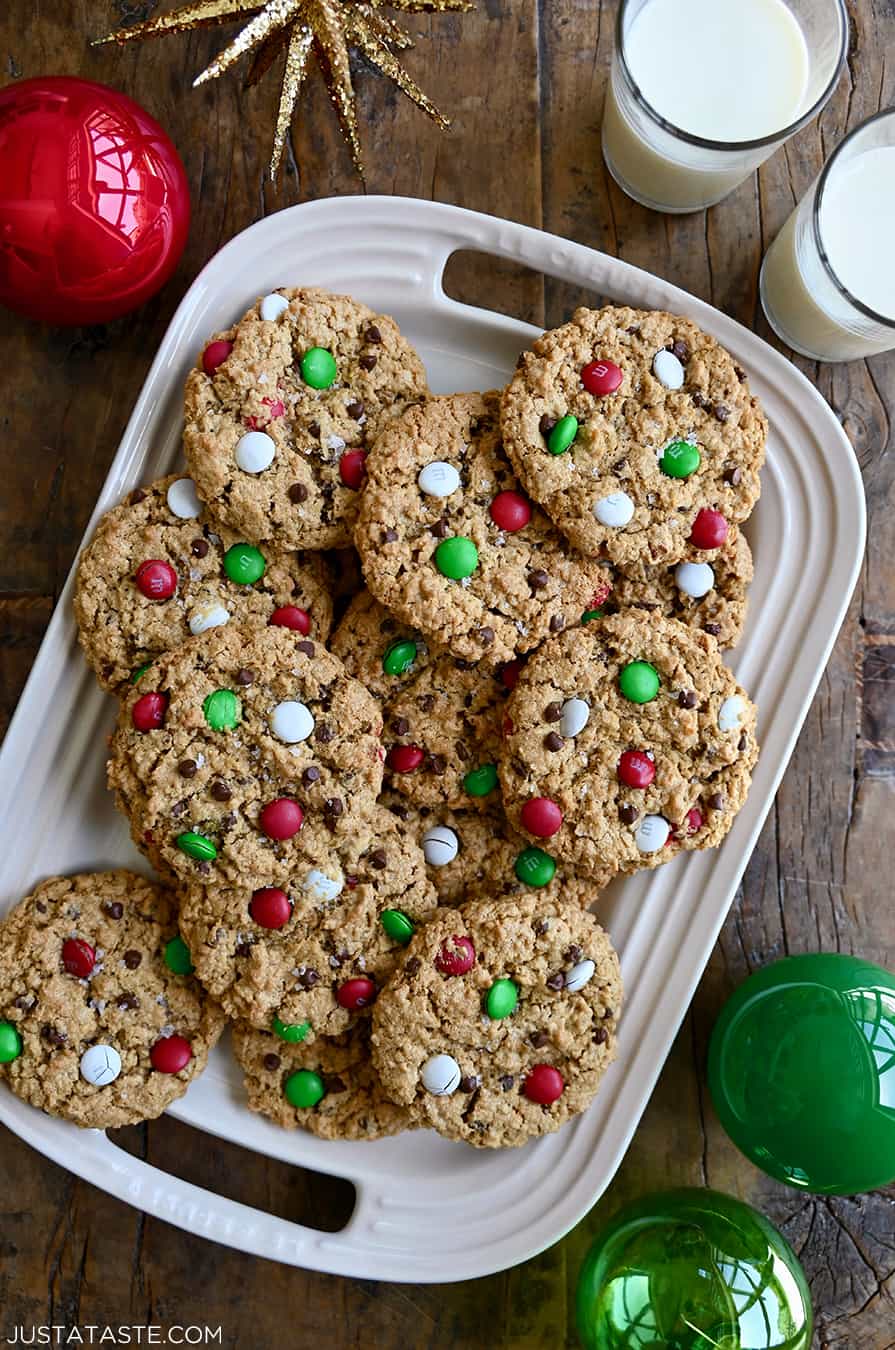 A top-down view of the best Christmas Monster Cookies studded with red, green and white M&Ms on a white serving platter