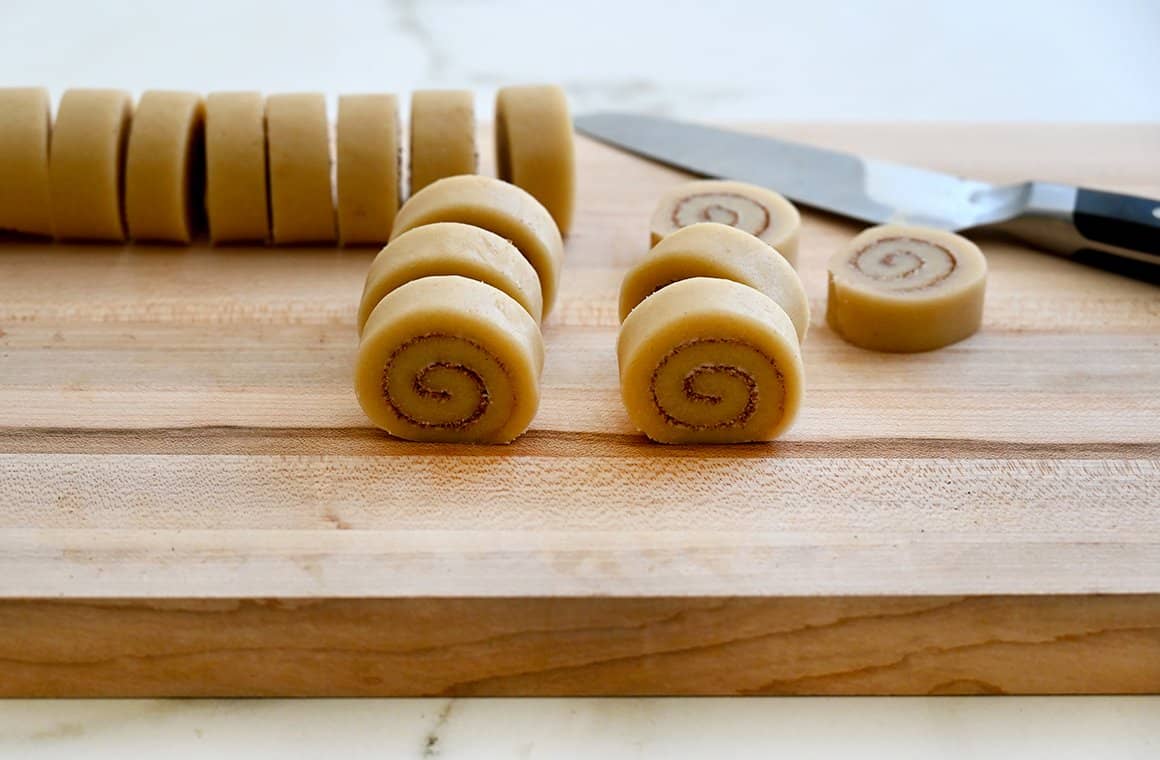 Slice-and-bake cookies on a cutting board with a sharp knife