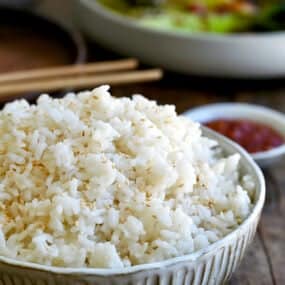 A bowl containing the best creamy coconut rice garnished with white sesame seeds