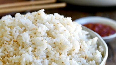 A bowl containing the best creamy coconut rice garnished with white sesame seeds