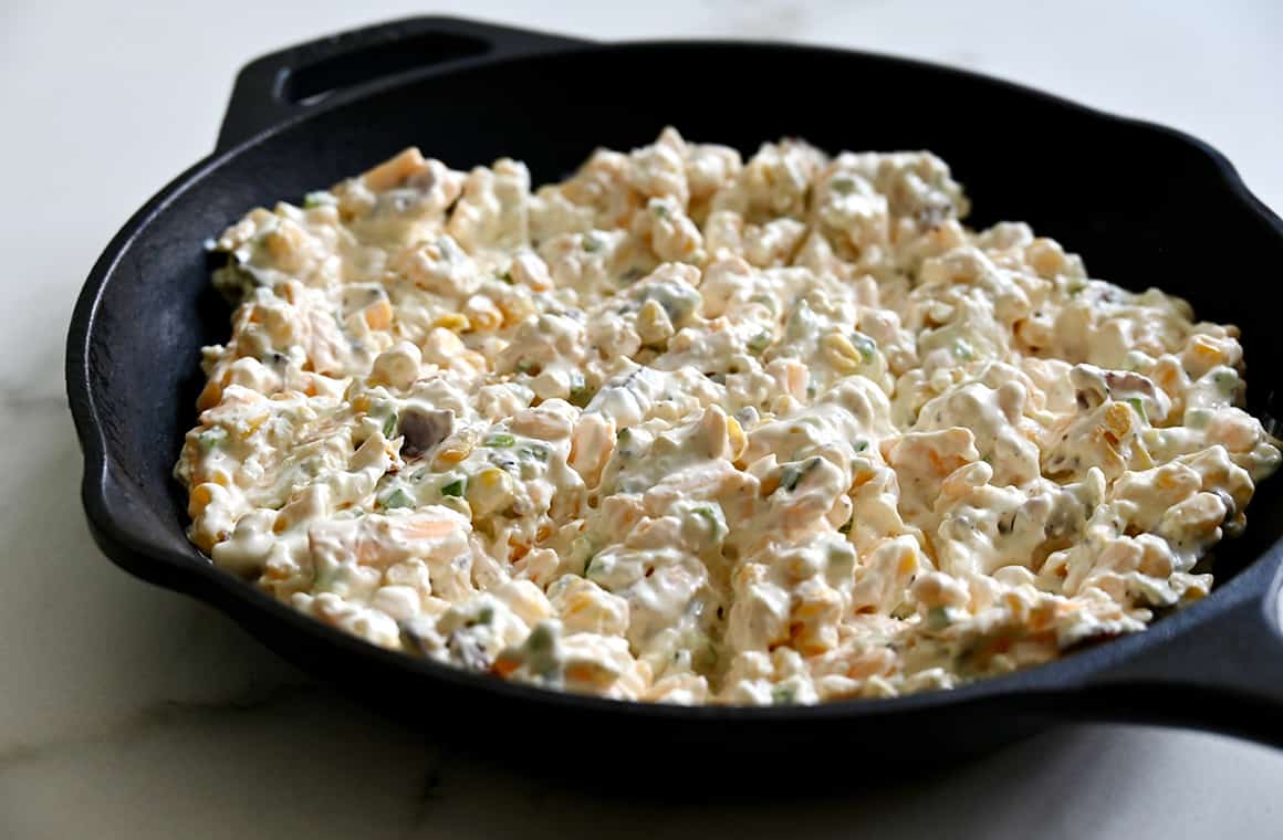 A cast iron skillet containing unbaked dip