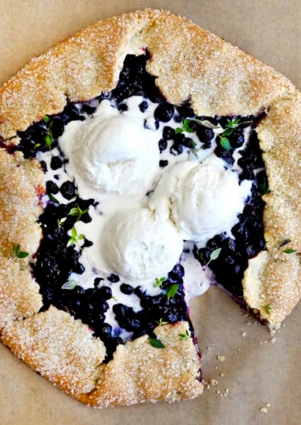 A blueberry galette with a thyme crust topped with three scoops of vanilla ice cream.