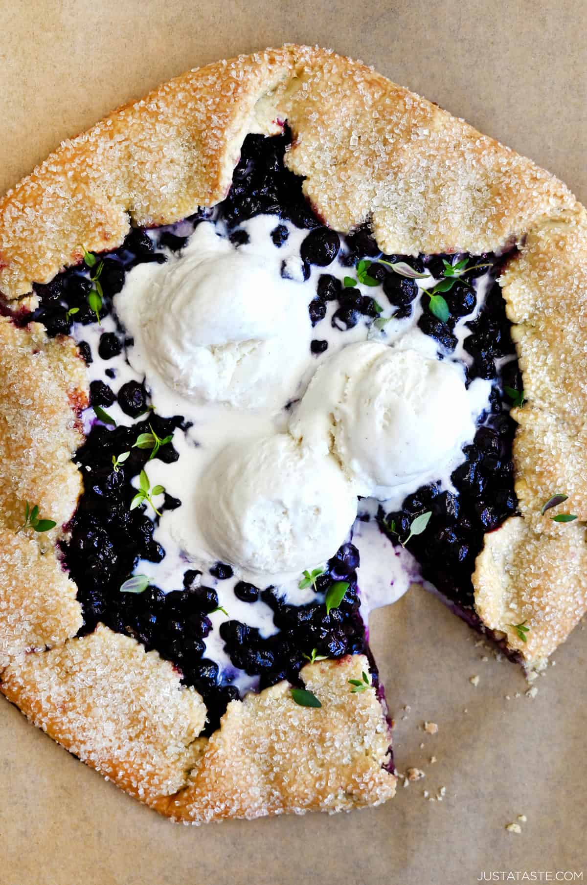A blueberry galette with a thyme crust topped with three scoops of vanilla ice cream.