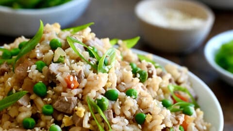 A white bowl containing Pork Fried Rice with peas and carrots