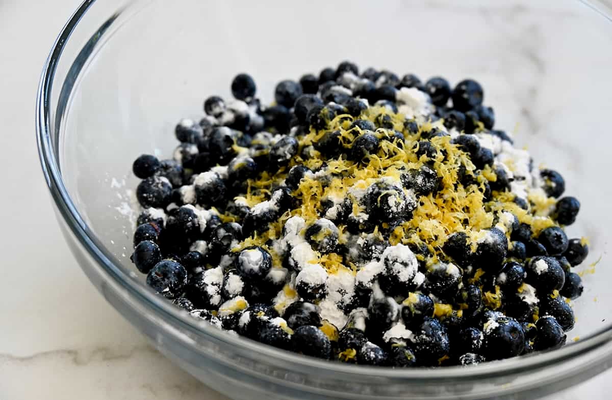 Fresh blueberries in a bowl topped with lemon zest and sugar.