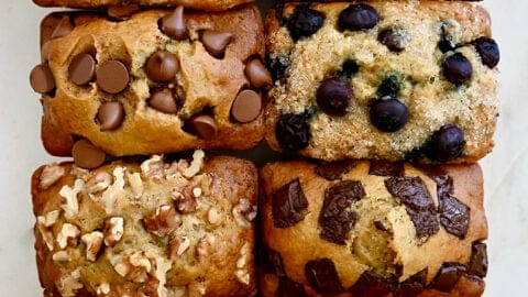 A top-down view of Mini Banana Bread Loaves studded with various mix-ins, including raspberries, chocolate chips, walnuts, sprinkles and more
