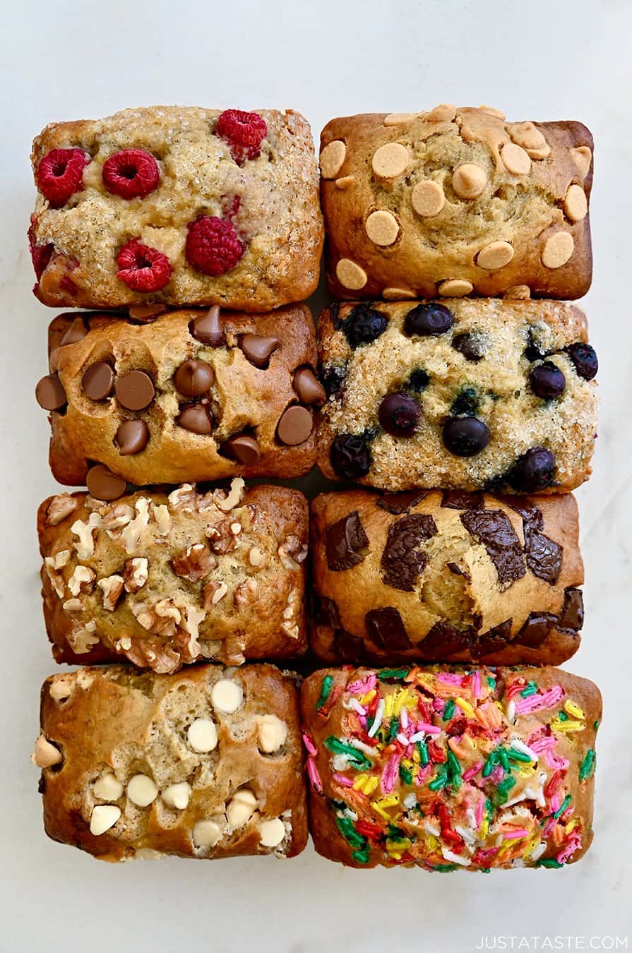 A top-down view of Mini Banana Bread Loaves studded with various mix-ins, including raspberries, chocolate chips, walnuts, sprinkles and more