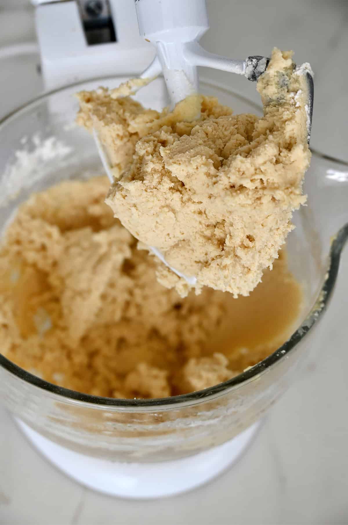Sugar cookie dough in a stand mixer bowl with the paddle attachment.