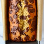 A top-down view of Olive Oil Banana Bread in a parchment paper-lined bread pan.