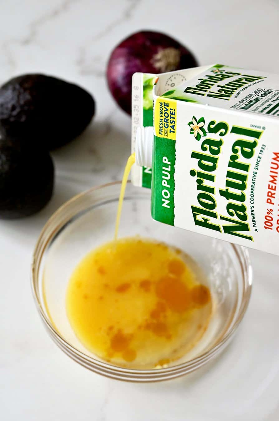 A carton of Florida's Natural orange juice being poured into a glass bowl