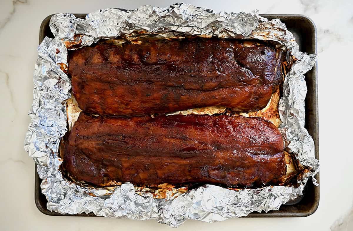 Barbecue ribs atop a foil-lined baking sheet.