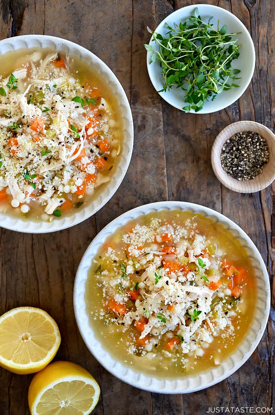 A top-down view of two bowls filled with the best leftover turkey soup next to a lemon cut in half and a small bowl containing micro greens