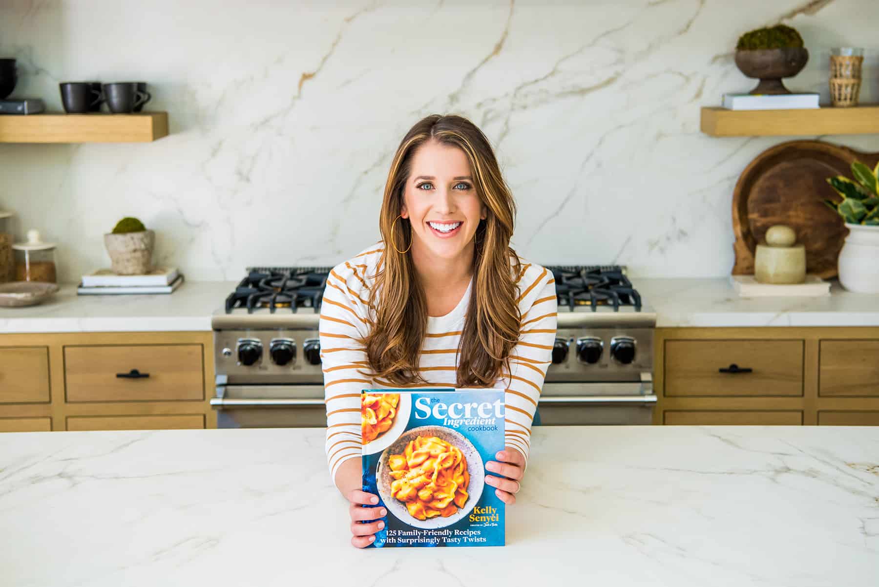 Kelly Senyei holding a copy of The Secret Ingredient Cookbook