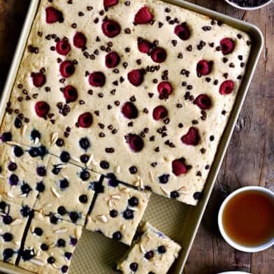 A top-down view of sheet pan pancakes topped with fresh berries and nuts