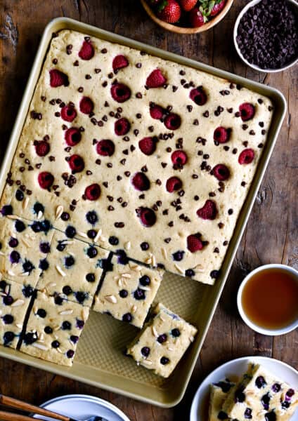 A top-down view of sheet pan pancakes topped with fresh berries and nuts