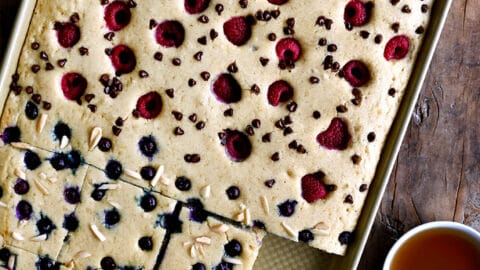 A top-down view of sheet pan pancakes topped with fresh berries and nuts