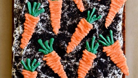 A top-down view Carrot Sheet Cake with Cream Cheese Frosting, Oreo dirt and candy melt carrots