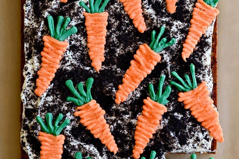 A top-down view Carrot Sheet Cake with Cream Cheese Frosting, Oreo dirt and candy melt carrots