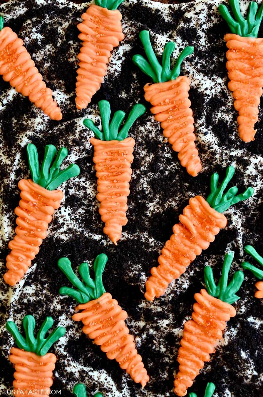 A close-up view of cream cheese frosting topped with Oreo dirt and candy melt carrots