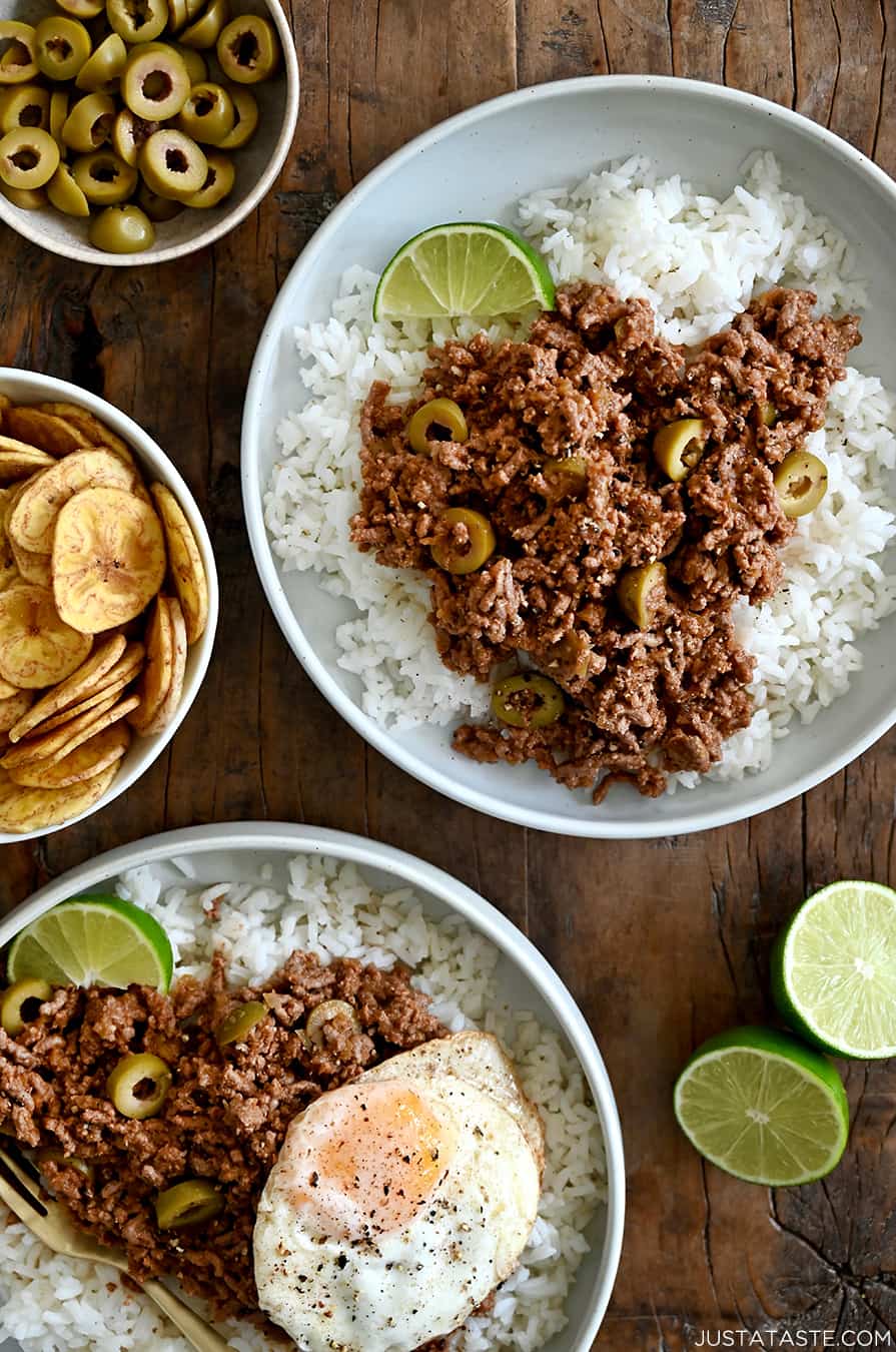 A top-down view of two plates containing white rice topped with Cuban Picadillo and a fried egg