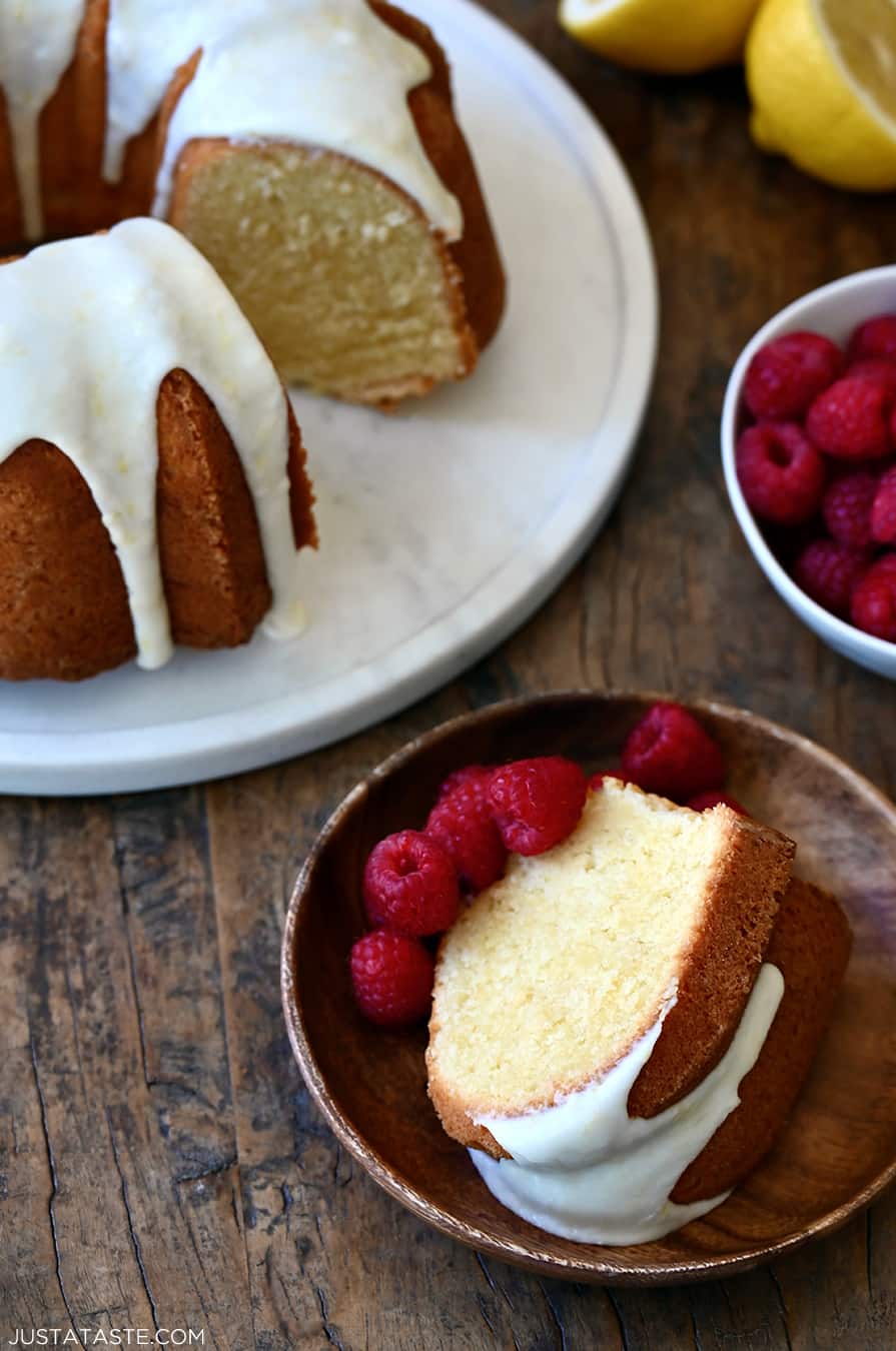 A slice of lemon cream cheese pound cake on a plate with fresh raspberries