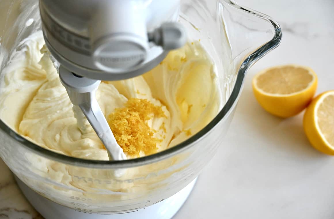 A stand mixer bowl containing batter topped with citrus zest