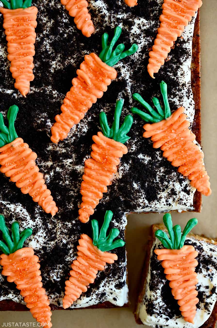 Easy carrot cake topped with frosting, crushed Oreos and candy melts in the shape of carrots