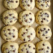A top-down view of banana chocolate chip cookies garnished with large-flake sea salt atop parchment paper.