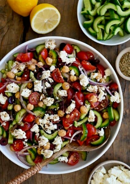 Greek cucumber tomato salad with feta and chickpeas, all tossed in a lemony red wine vinaigrette in a large serving bowl.