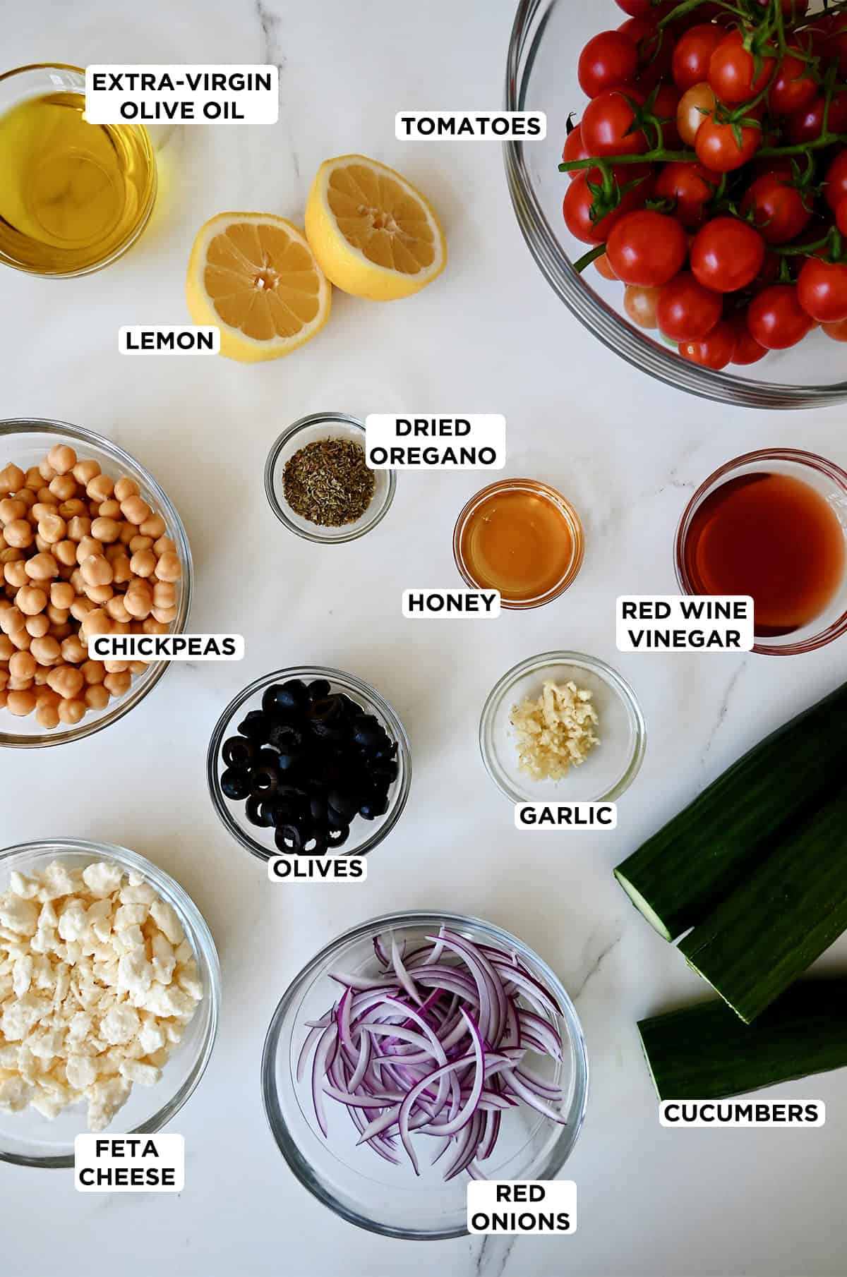 Greek cucumber salad ingredients in various sizes of prep bowls.