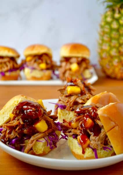 Slow cooker Hawaiian pulled pork with pineapple chunks and barbecue sauce on slider buns.