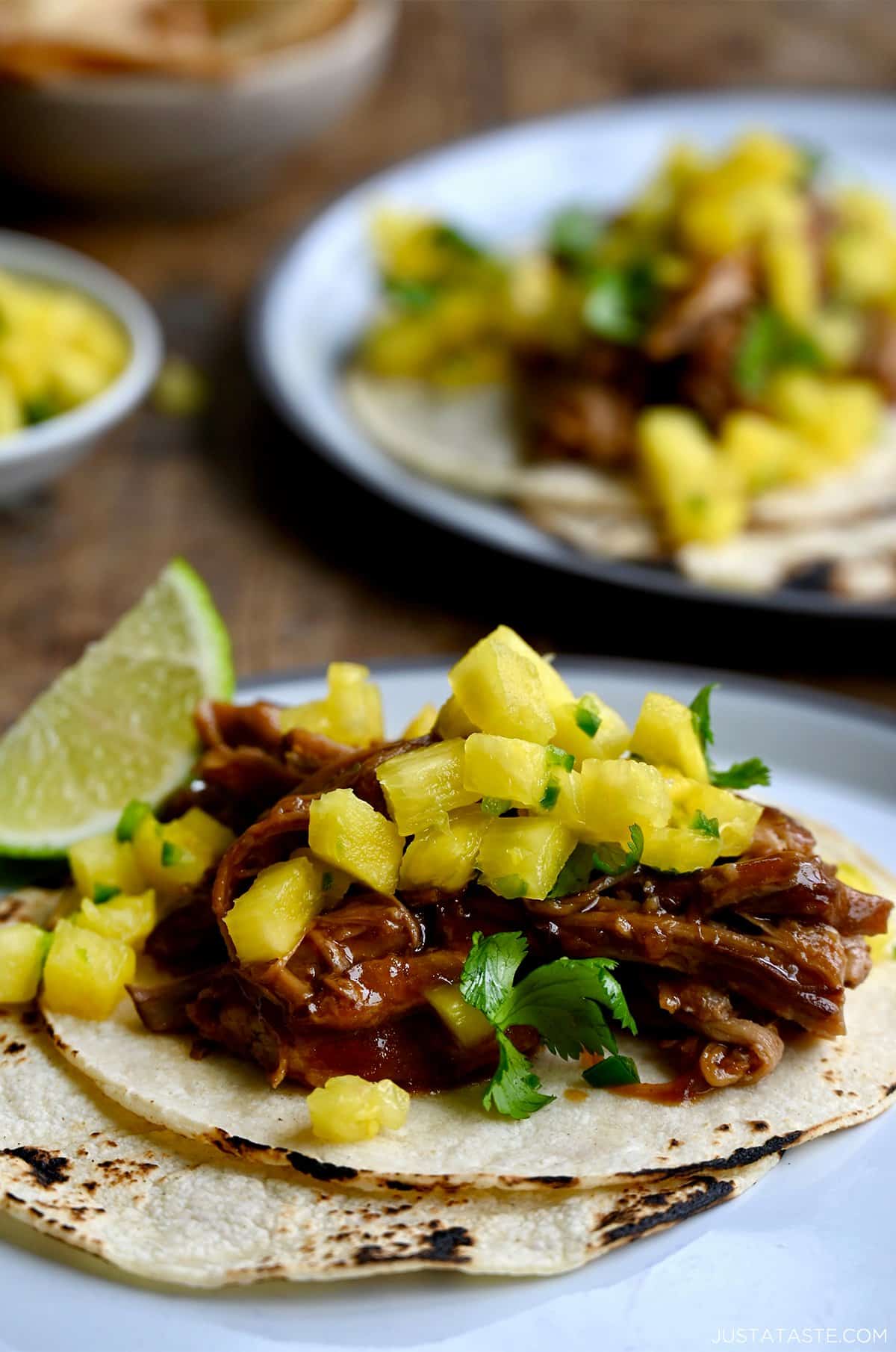 Shredded pulled pork with pineapple chunks, and a sweet and savory sauce on tortillas.