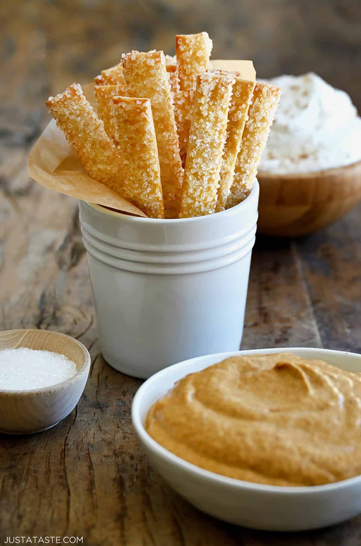 A white container with pie crust fries in parchment paper.