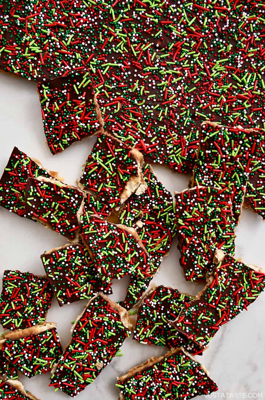 A top-down view of broken apart Saltine Cracker Toffee topped with an assortment of red, green and white sprinkles
