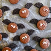 A top-down view of Oreo Bat Cookies covered in chocolate with bloody candy eyes.
