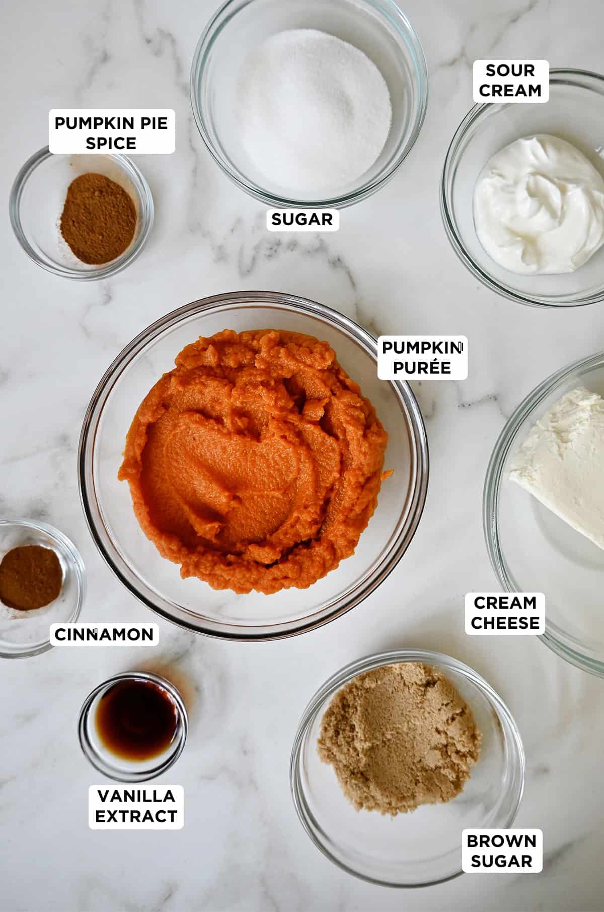 Ingredients to make pumpkin cheesecake dip in various-sized prep bowls.