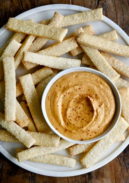 Creamy no-bake pumpkin dip made with cream cheese in a small bowl on a plate with pie crust fries.