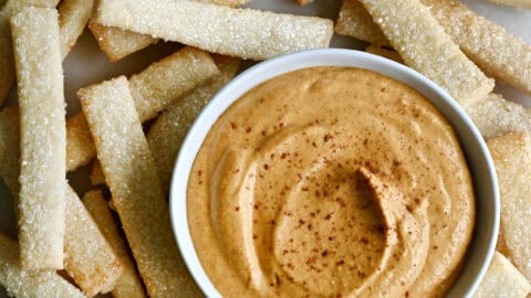 Creamy no-bake pumpkin dip made with cream cheese in a small bowl on a plate with pie crust fries.