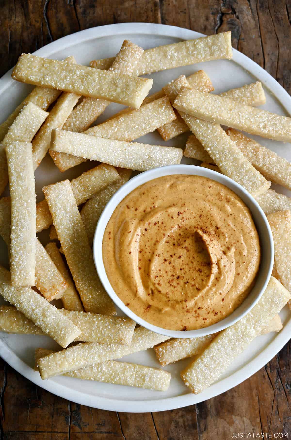 Creamy no-bake pumpkin dip made with cream cheese in a small bowl on a plate with pie crust fries.