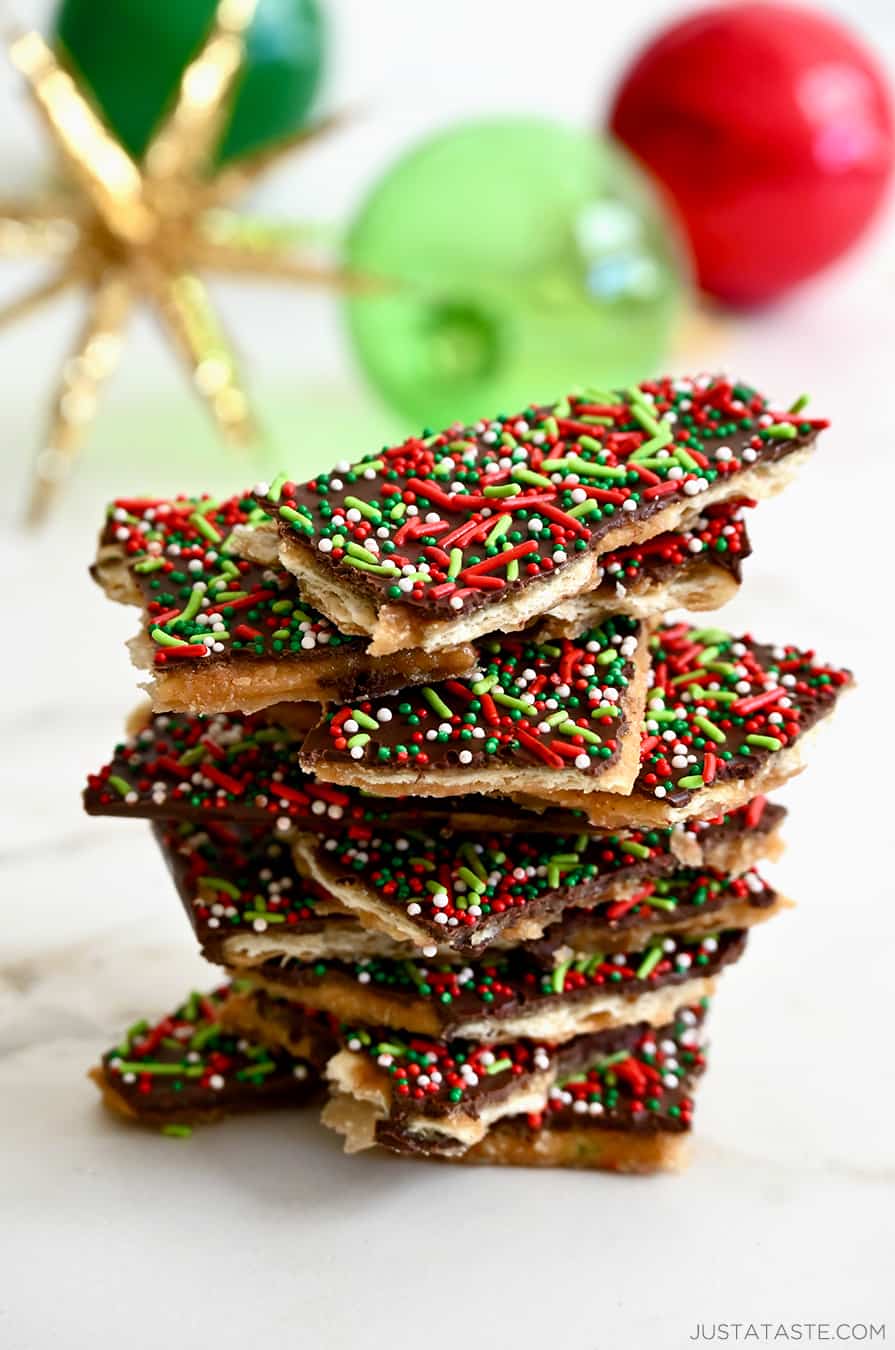 Un'alta pila di Christmas Saltine Cracker Toffee davanti a ornamenti per le vacanze