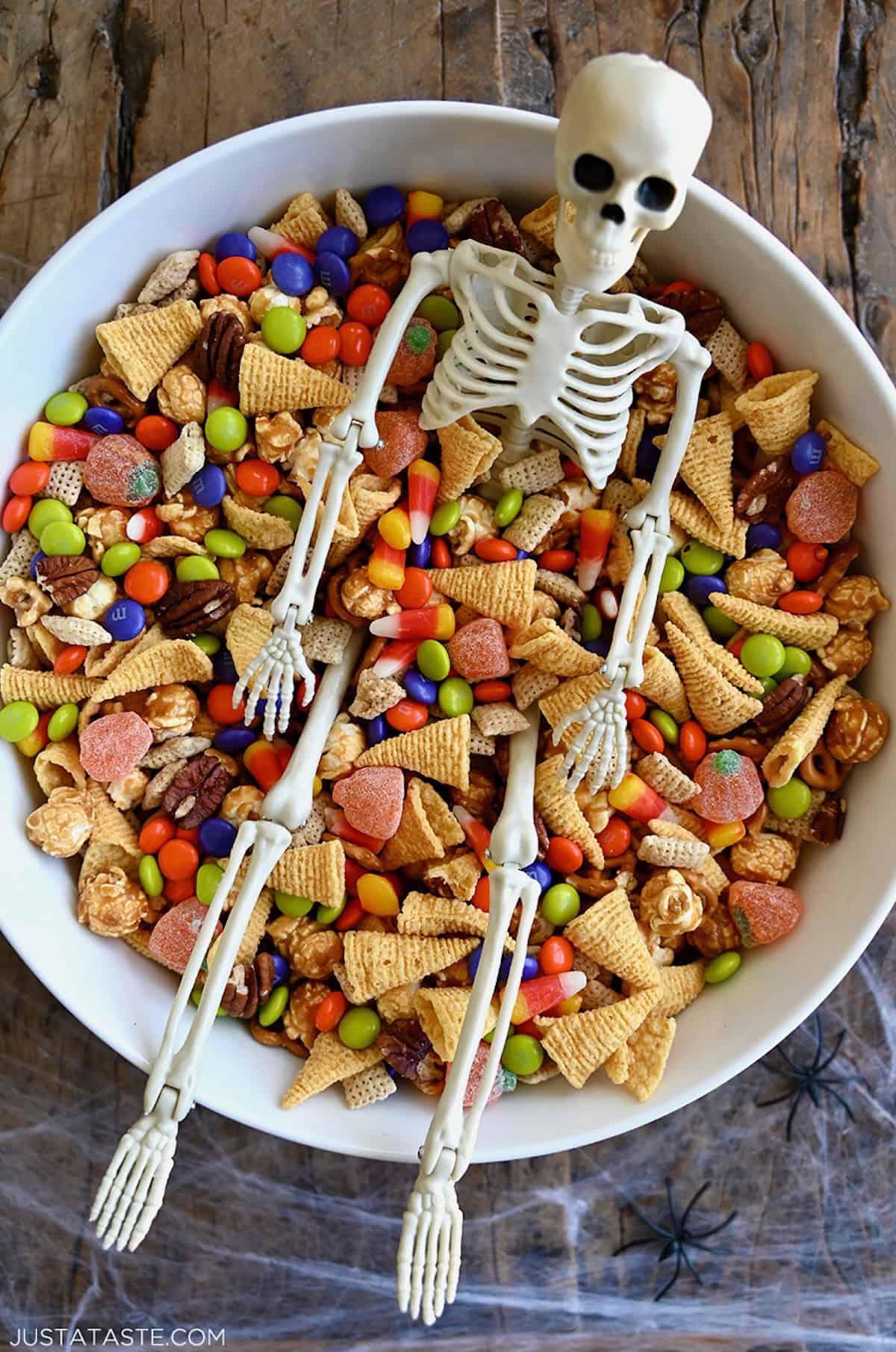 Spooky party mix with a plastic skeleton in a large serving bowl.