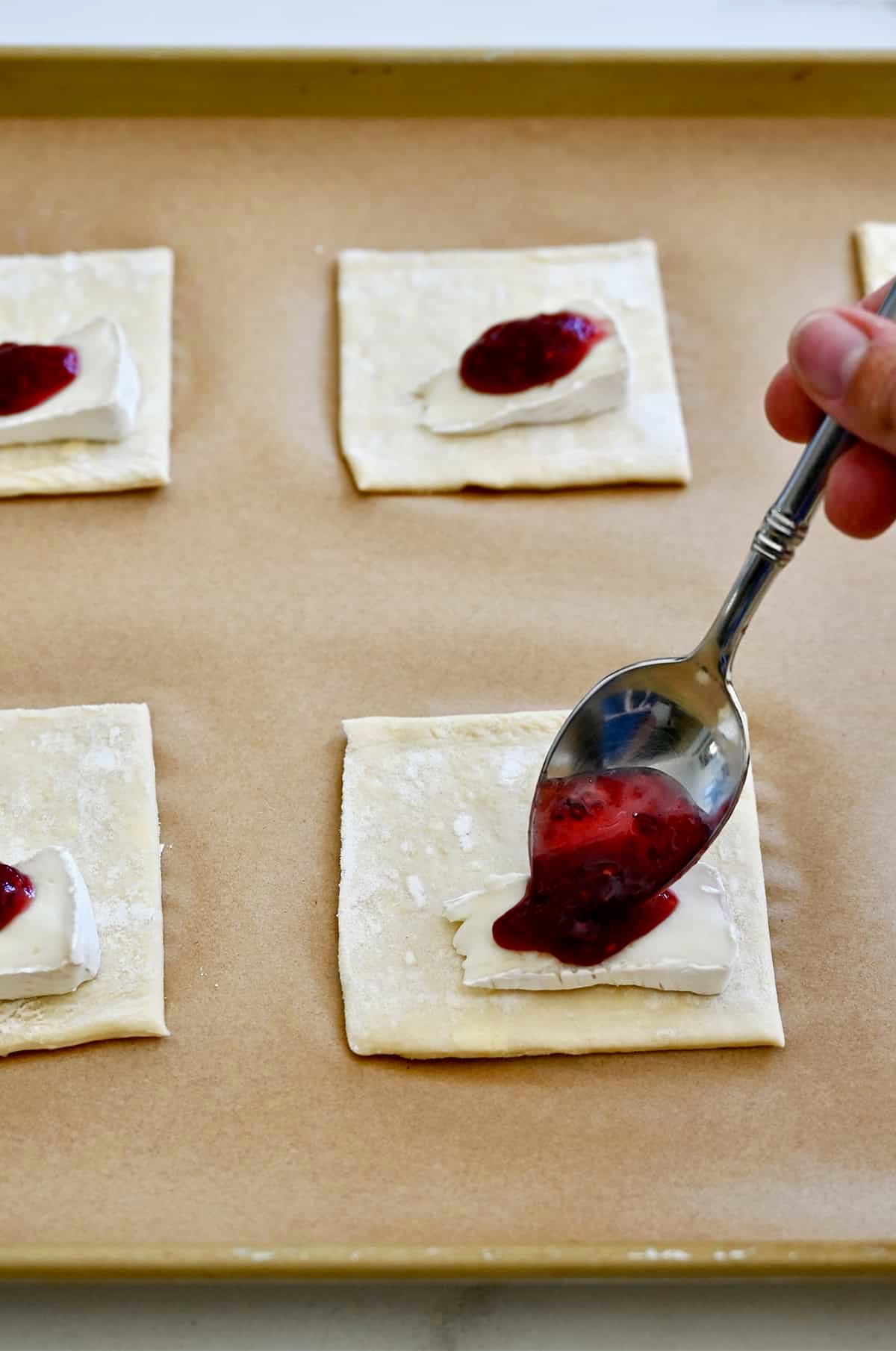 Adding a dollop of raspberry jam atop a thin slice of Brie on puff pastry.